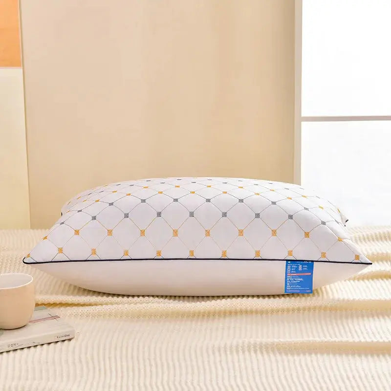 Almohada rectangular blanca con elegante patrón geométrico de rombos y detalles dorados, demostrando un rebote suave sobre un fondo cálido