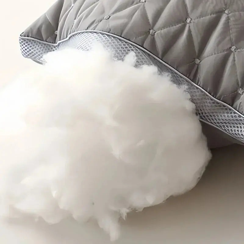 Primer plano del relleno interior de fibra de alta densidad de la almohada gris hotelera, saliendo por la cremallera, demostrando el núcleo 'anti-colapso'